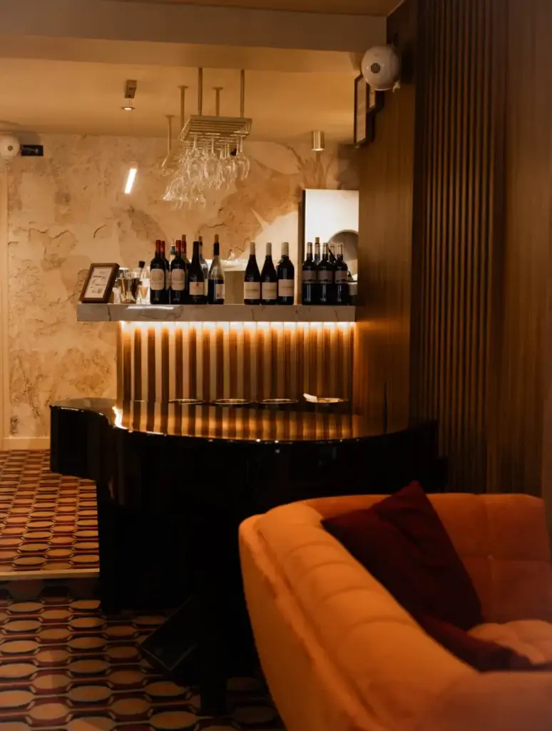 Intérieur du restaurant Madie à Paris 8 avec piano noir et bar à vins éclairé