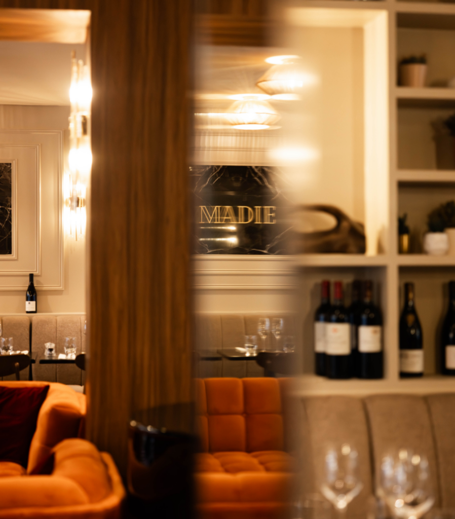 Reflet du restaurant Madie dans un miroir, avec le logo doré et l’ambiance chaleureuse de la salle.