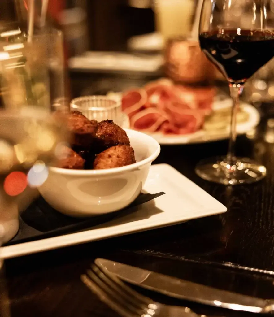 Assiette d’apéritifs et verre de vin rouge sur une table au restaurant Madie à Paris 8