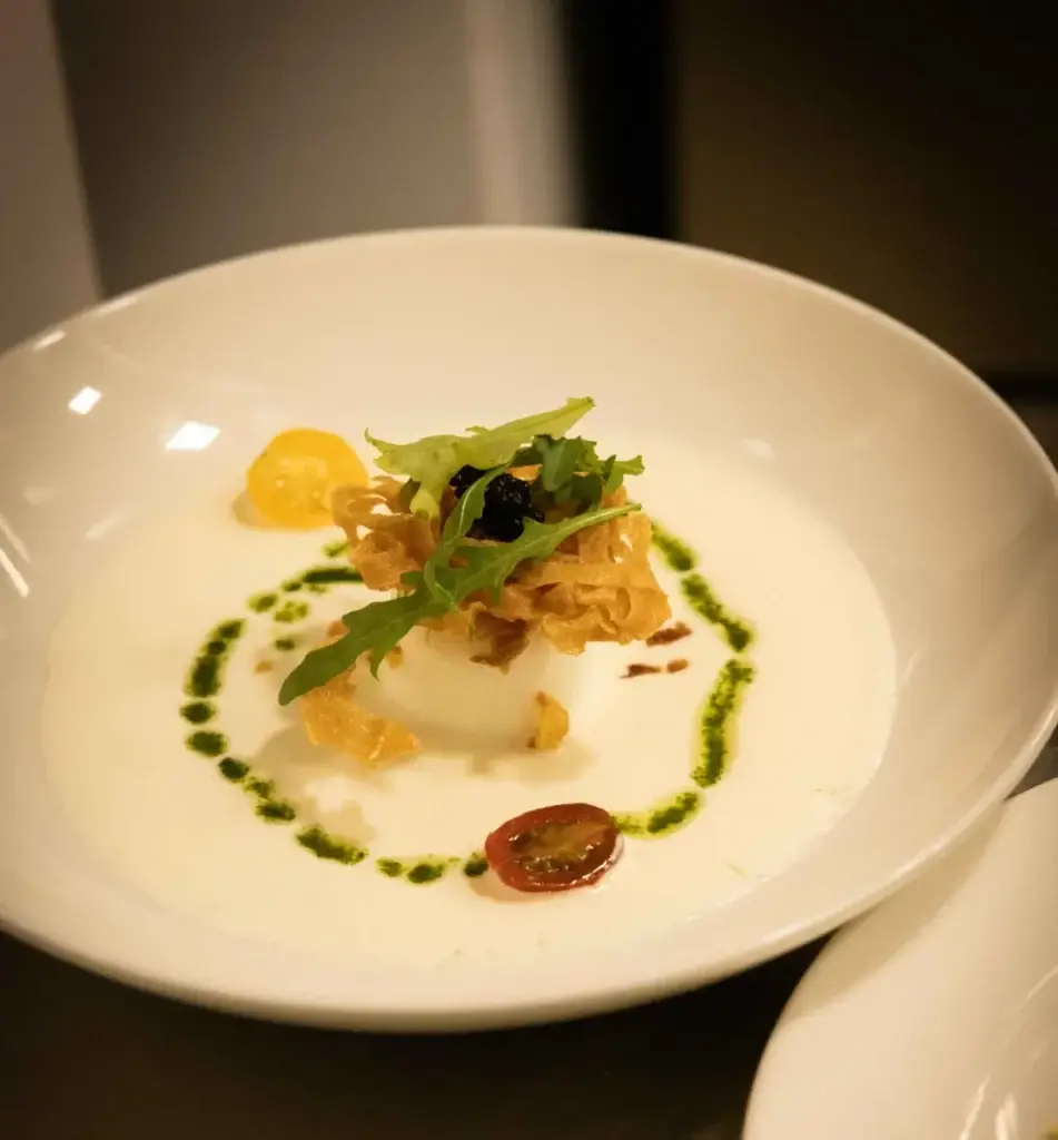 Entrée gastronomique crémeuse dressée avec herbes fraîches, croustillant et tomates au restaurant Madie Paris 8